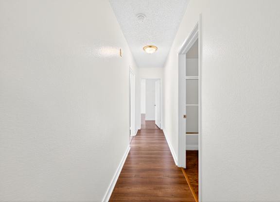 A long hallway with white walls and wood floors.