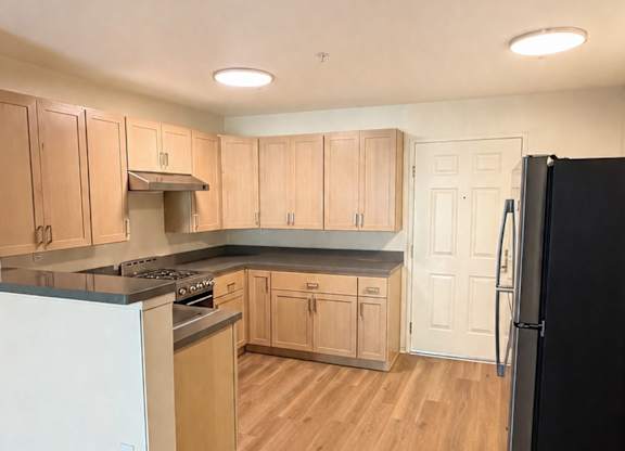 A kitchen with wooden floors and white appliances.