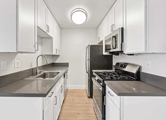 A kitchen with white cabinets and a black stove top oven.