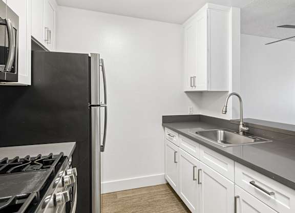 A kitchen with a black fridge and white cabinets.
