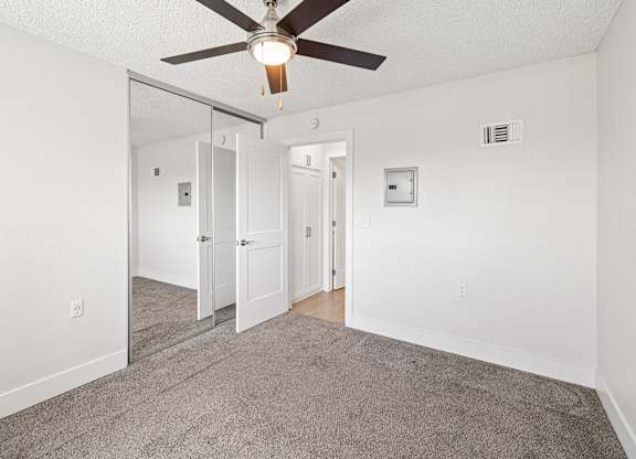 A room with a ceiling fan and carpeted floor.