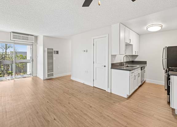 A kitchen with white cabinets and a wooden floor.