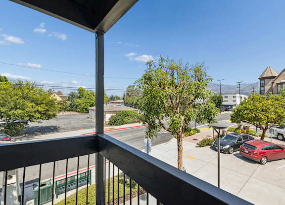 A balcony view of a parking lot with cars and trees.