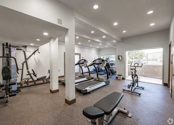A spacious gym with a variety of equipment including treadmills, exercise bikes, and weight machines at Oak Park Apartments, Monrovia, 91016