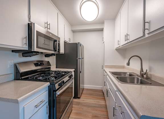A kitchen with a stove, microwave, and refrigerator at Oak Park Apartments, Monrovia, 91016