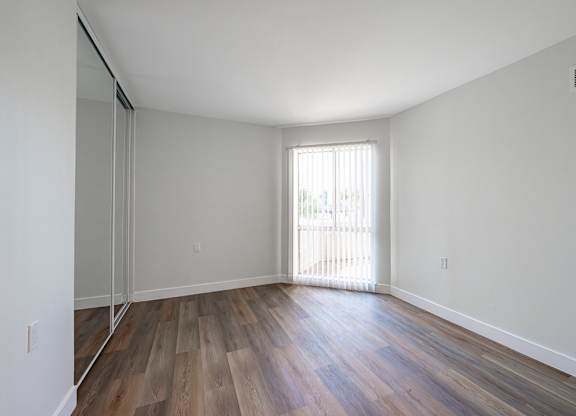 A room with wooden floors and a window with blinds at Oak Park Apartments, Monrovia, 91016