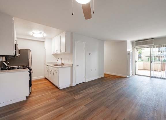 A kitchen with white cabinets and a wooden floor at Oak Park Apartments, Monrovia, 91016