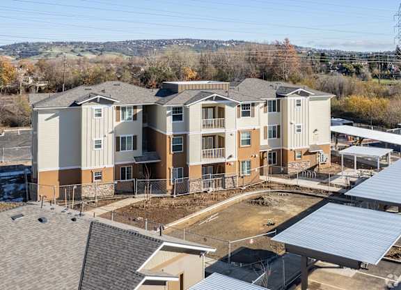 A large, multi-story residential building with a parking lot in front.