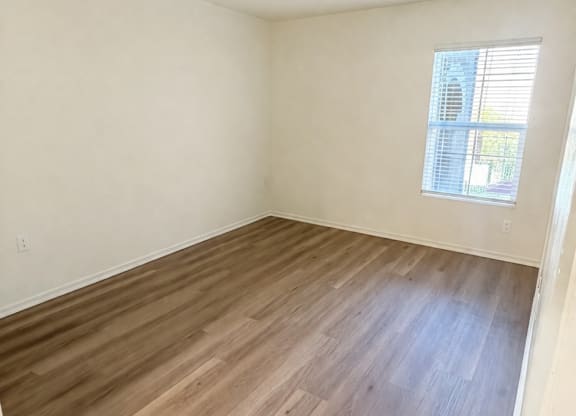 A room with wooden flooring and a window.