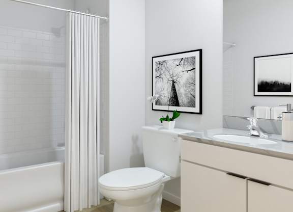 A white bathroom with a toilet, sink, and a framed picture on the wall.
