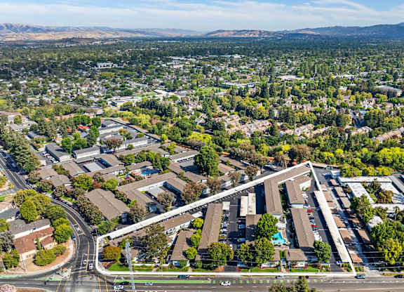 A large building complex is surrounded by a green landscape.