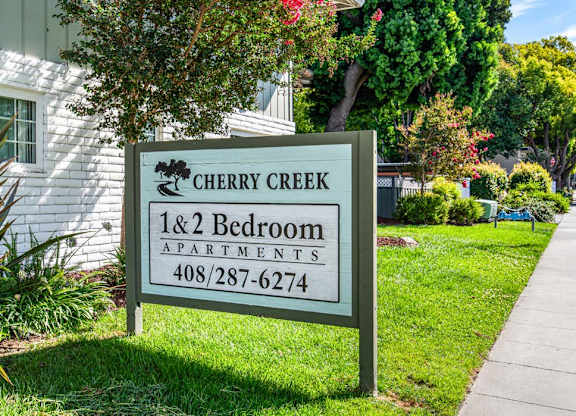 A sign for Cherry Creek 1 & 2 Bedroom Apartments is in front of a building.