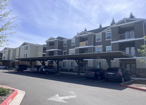 A parking lot in front of a large apartment complex.