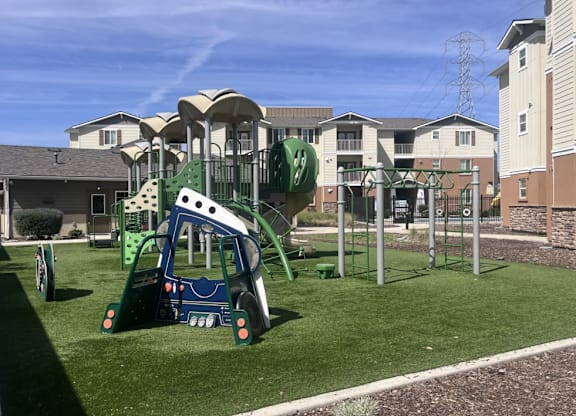 A playground with a green slide and a white and blue play structure.