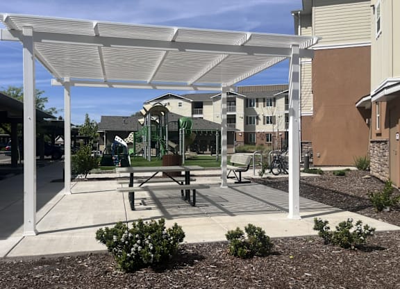A white canopy structure is over a picnic table.