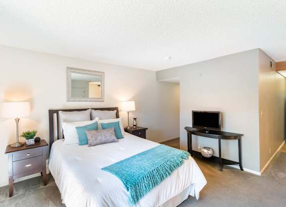 A bedroom with a large bed and a television at Chaparral Apartments, Palmdale, CA
