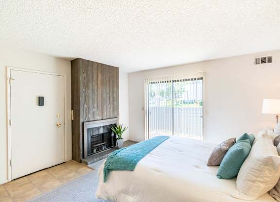 A bedroom with a large bed and a fireplace. at Chaparral Apartments, California, 93551