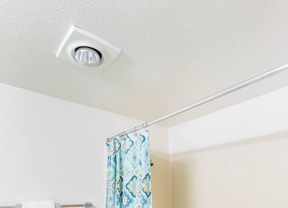 A bathroom with a shower curtain and a towel hanging on the wall at Chaparral Apartments, California, 93551