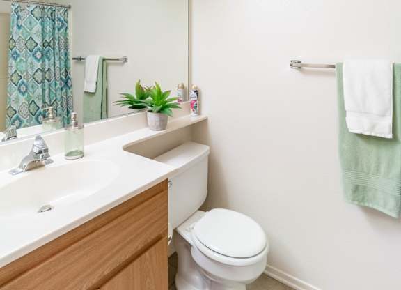 A white toilet sits in a bathroom next to a sink at Chaparral Apartments, California