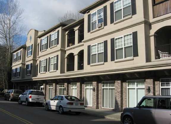 A row of townhouses with cars parked in front.