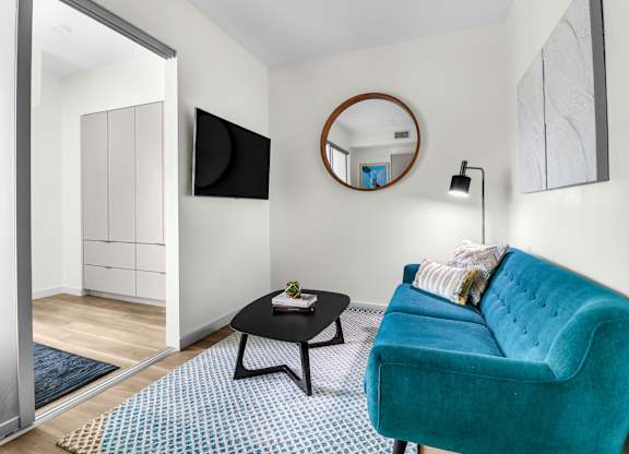 a living room with a blue couch and a round mirror on the wall
