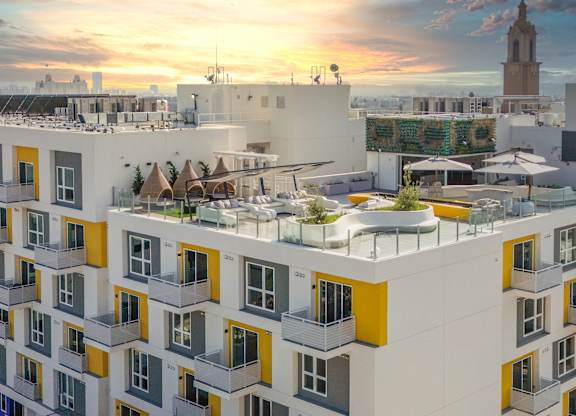 a rendering of a building with a green roof and a sunset in the background