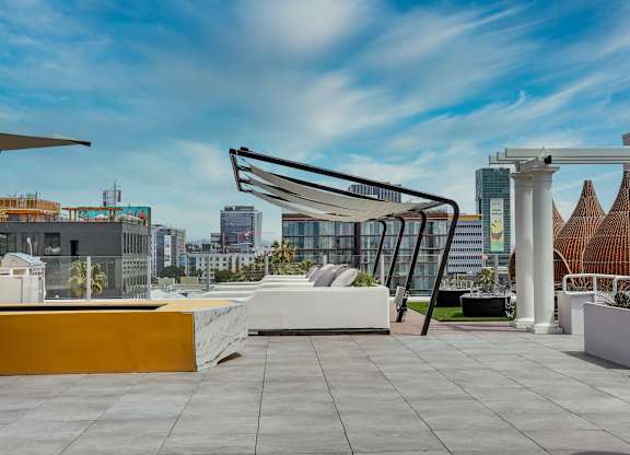 an outdoor terrace with a white couch and yellow table with white pillows and a white