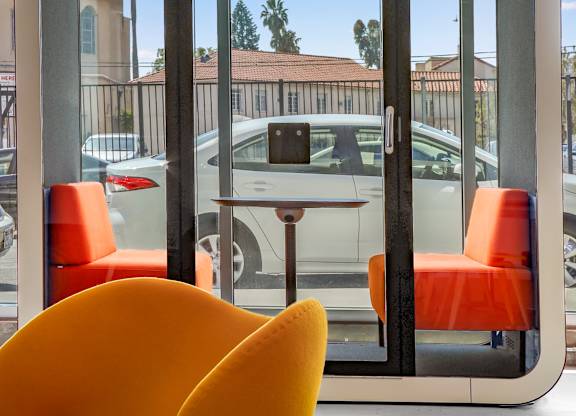 a seating area with orange chairs and a table in front of a window