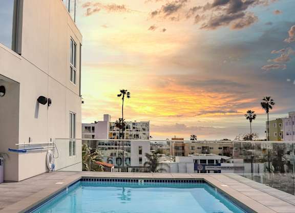 a view of the pool and sunset from a hotel room