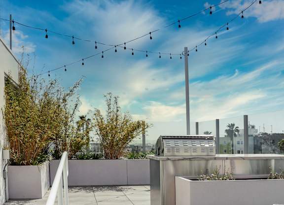 a rooftop terrace with a barbecue grill and a string of lights
