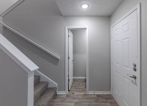 A hallway with a staircase and a door.