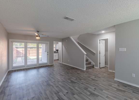 A spacious room with a staircase and sliding glass doors.