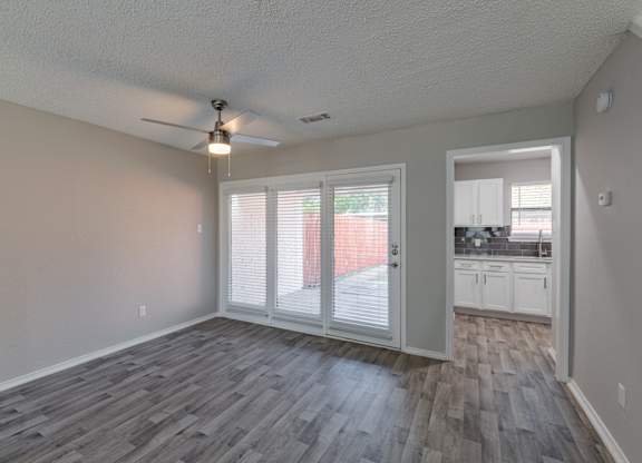 A room with a ceiling fan and sliding glass doors.