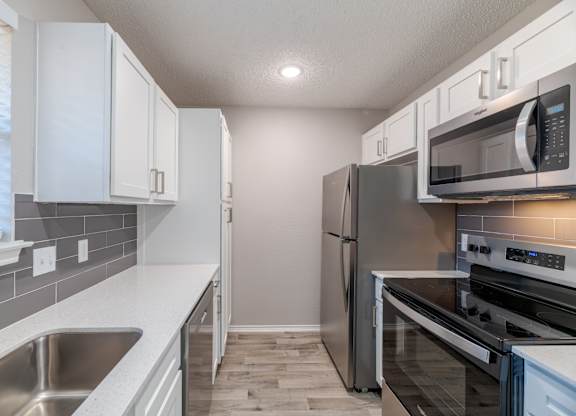 A kitchen with stainless steel appliances and white cabinets.