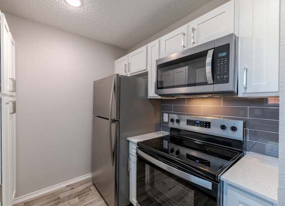 A kitchen with a stainless steel refrigerator, microwave, and oven.