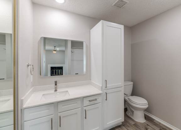 A white bathroom with a sink, toilet, and medicine cabinet.