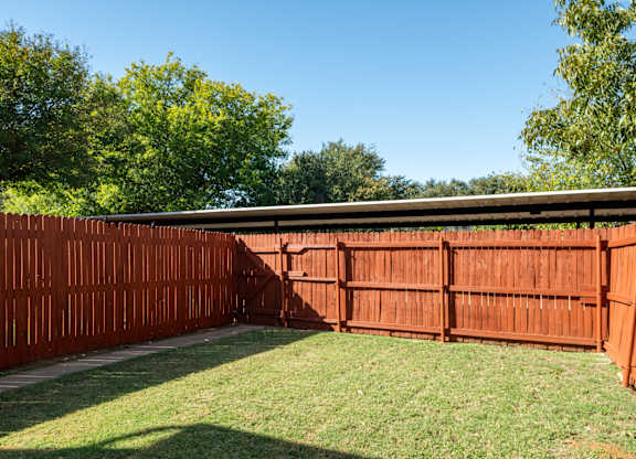 A brown fence encloses a green lawn.