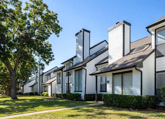 A row of white houses with dark roofs and chimneys.