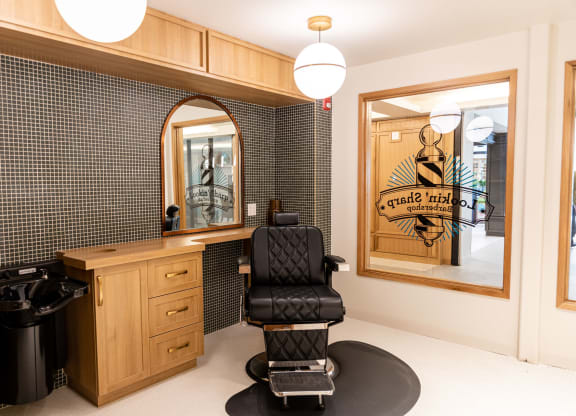 a salon room with a black chair and a black and white tiled wall