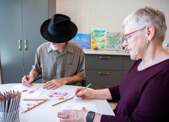 a man and a woman sitting at a table painting