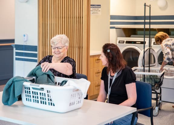 a woman sitting at a table with a laundry basket in front of her