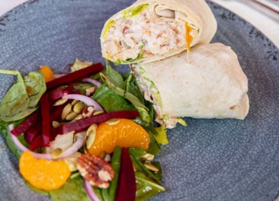 a sandwich and salad on a plate with a glass of orange juice