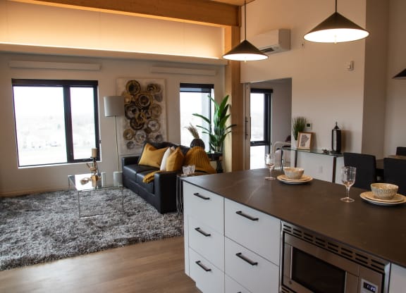 a kitchen with a large center island next to a living room with a couch and a coffee