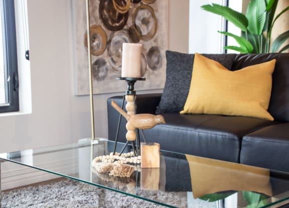 a living room with a black leather couch and a glass coffee table