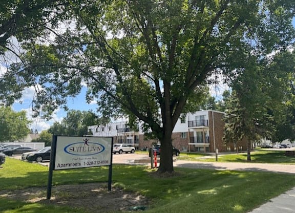 A tree stands in front of a Suite Living apartment complex.