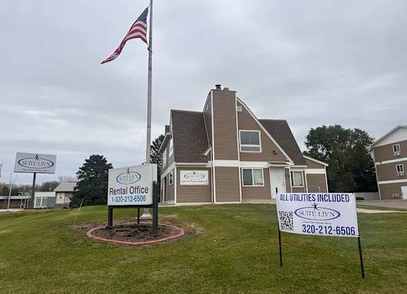 A rental office sign in front of a house with an American flag.