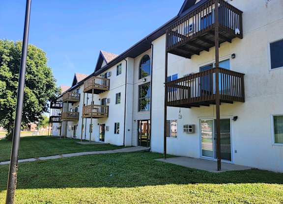 A white building with balconies and a green lawn in front.