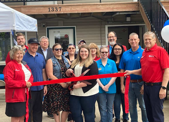 A group of people are gathered for a ribbon cutting ceremony.