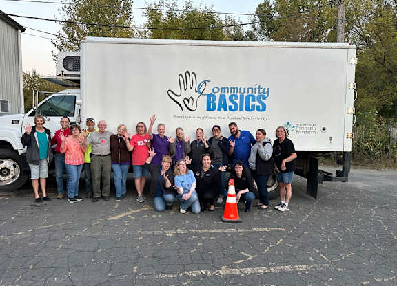 A group of people are standing in front of a Community Basics truck.