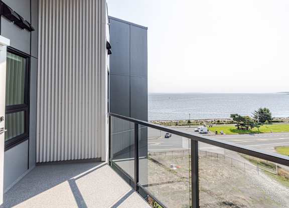 A balcony with a view of the ocean and a parking lot.